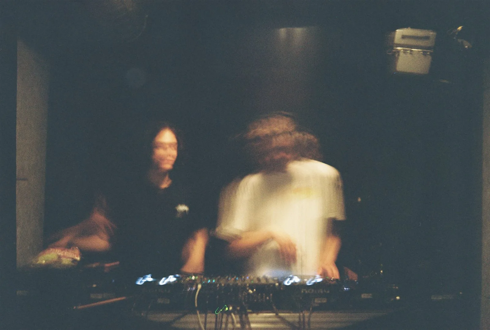 Two figures behind the decks