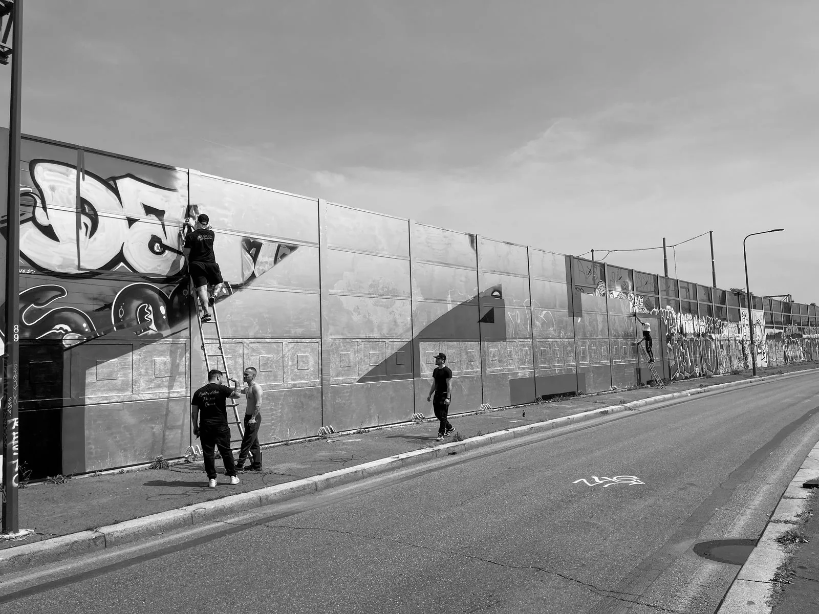 Writers on a ladder hitting a sound wall in daylight